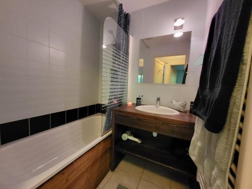 une salle de bain avec un lavabo, une baignoire et un miroir dans l'établissement Appartement dans châlet avec piscine couverte, à Saint-Gervais-les-Bains