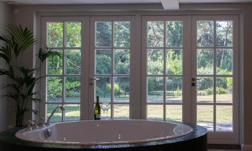 a bath tub in front of a large window at Guesthouse "Mirabelle" met indoor jacuzzi, sauna & airco in Tilburg