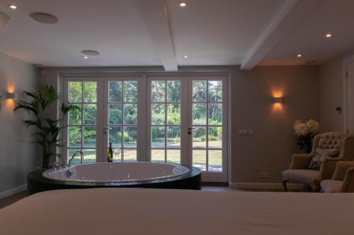 Guesthouse "Mirabelle" met indoor jacuzzi, sauna & airco في تيلبورغ: غرفة كبيرة مع حوض استحمام أمام النوافذ