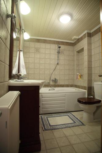 a bathroom with a tub and a toilet and a sink at Menelia Cottage in Platístoma
