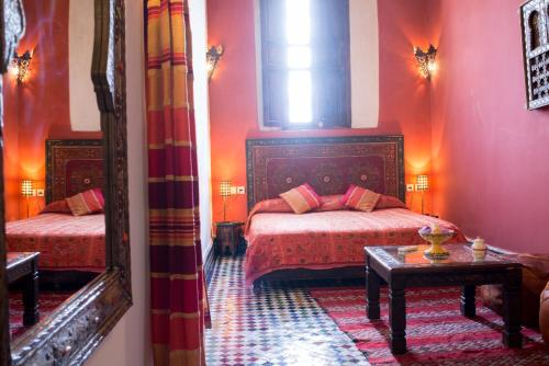 a bedroom with two beds and a table and a mirror at Riad Tafilalet in Fès