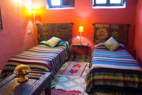two beds sitting in a room with orange walls at Riad Tafilalet in Fès