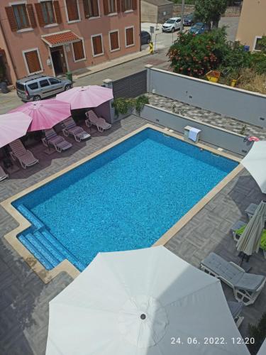 een uitzicht over een zwembad met parasols bij Apartmant & rooms Villa Rosa Medulin in Pomer