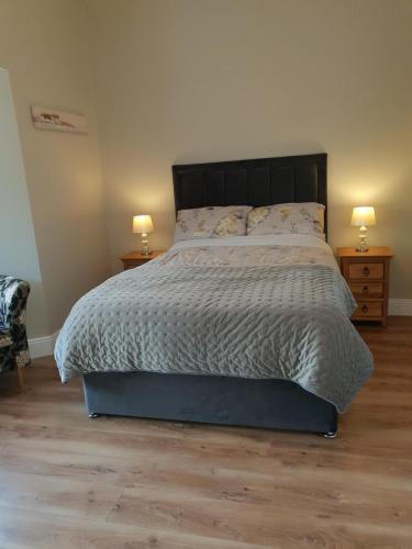 um quarto com uma cama grande e 2 mesas de cabeceira em Beechwood Lodge em Blarney