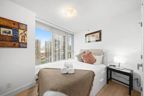a white bedroom with a bed and a window at Water View Condo in Downtown Vancouver (2BR/2Bath) in Vancouver