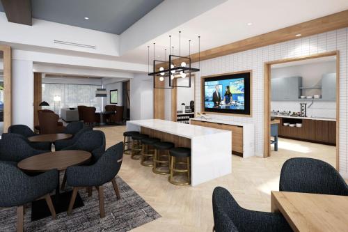a living room with tables and chairs and a kitchen at Staybridge Suites Wilmington Downtown by IHG in Wilmington