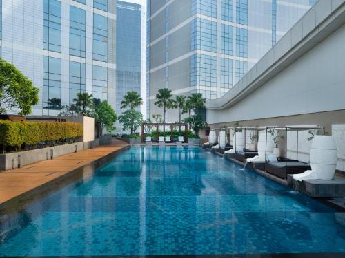a swimming pool in the middle of a building with tall buildings at InterContinental Hotels Jakarta Pondok Indah by IHG in Jakarta