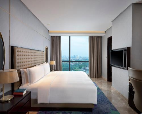 a bedroom with a large white bed and a large window at InterContinental Hotels Jakarta Pondok Indah by IHG in Jakarta