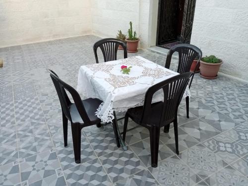 une table avec quatre chaises et un tissu de table blanc dans l'établissement Jerash air apartment, à Jerash