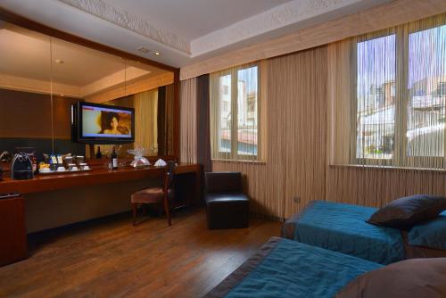 a hotel room with a desk and a bed and a television at Pera Tulip Hotel & Spa - Istanbul Taksim Pera City Center in Istanbul