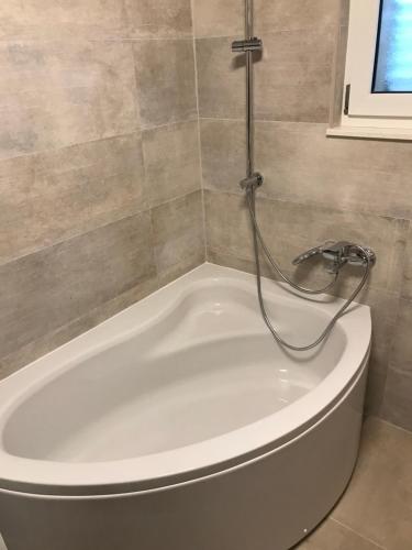 a white bath tub with a shower in a bathroom at Albatros in Kastel Sucurac