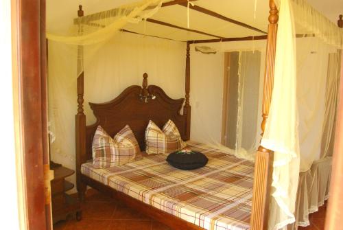 a bedroom with a canopy bed with pillows on it at Zum Deutschen in Bentota