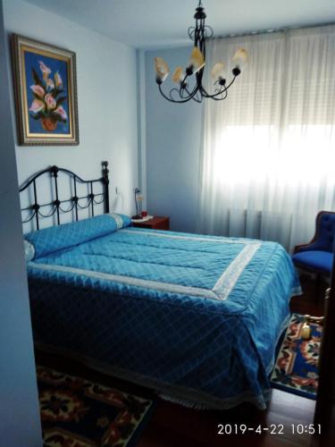 een slaapkamer met een blauw bed en een kroonluchter bij Puente Villanueva dreans in Medina de Pomar