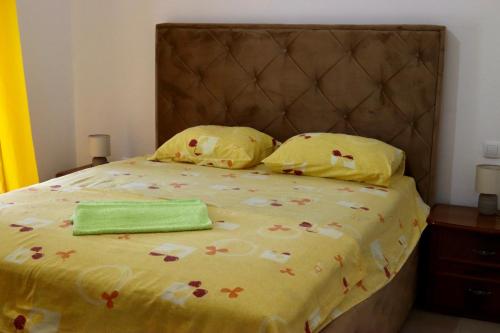 a bed with a yellow comforter with a green towel on it at Montebello Inn apartments in Ulcinj