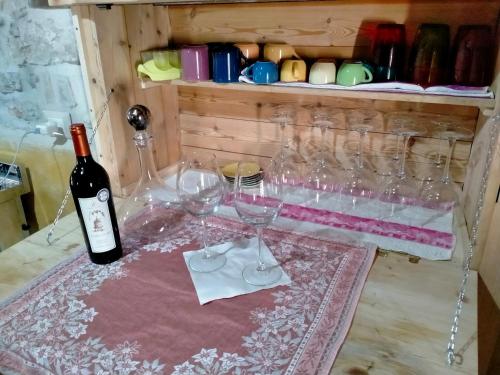 a bottle of wine sitting on a table with wine glasses at Maison en Pierre in Fiastra