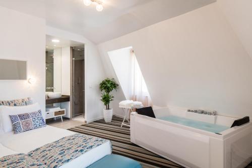 a bedroom with a tub and a bed and a sink at Marino Lisboa Boutique Guest House in Lisbon