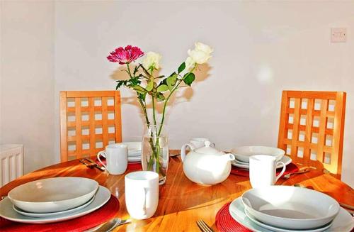 a white table topped with a white vase filled with flowers at Hillview House Hostel Inverness in Inverness