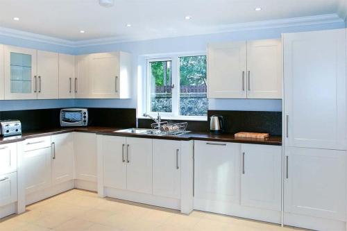 a white kitchen with white cabinets and a window at Hillview House Hostel Inverness in Inverness