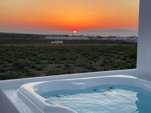 a bath tub with a view of a sunset at Anemi Vine Villas in Foinikiá