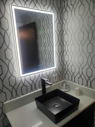 a bathroom with a black sink and a mirror at Alpine Inn Abbotsford in Abbotsford