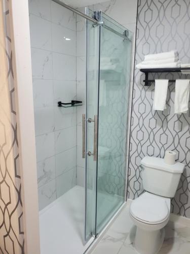 La salle de bains est pourvue d'une douche en verre et de toilettes. dans l'établissement Alpine Inn Abbotsford, à Abbotsford