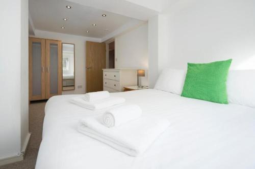 a white bedroom with a large white bed with a green pillow at North Laine City Centre sleeps 6 in Brighton & Hove