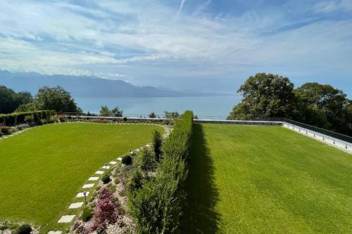 a large grassy field with the water in the background at Les Terrasses de Lavaux 1 - Appartement de luxe avec vue panoramique et piscine in Puidoux