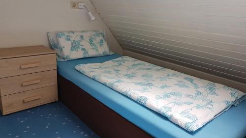 ein kleines Bett in einem kleinen Zimmer mit einer Kommode in der Unterkunft Ferienwohnung in Gartenlandschaft in Kassel