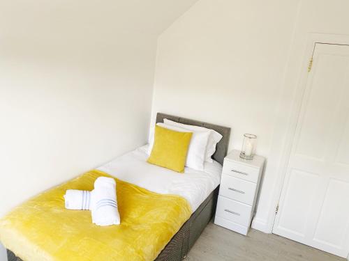 a bedroom with a bed with a yellow pillow and a night stand at Luxurious family home in West Midlands in Northfield