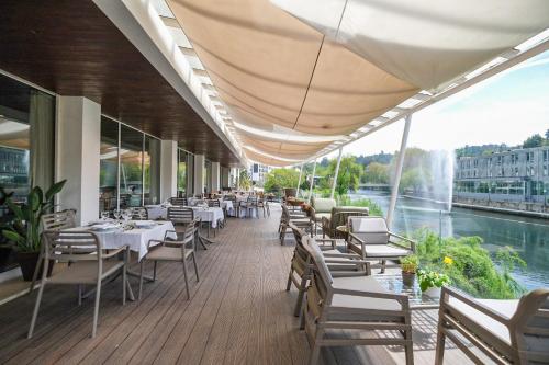 a restaurant with tables and chairs and a view of a river at Hotel Vouga in Termas de Sao Pedro do Sul