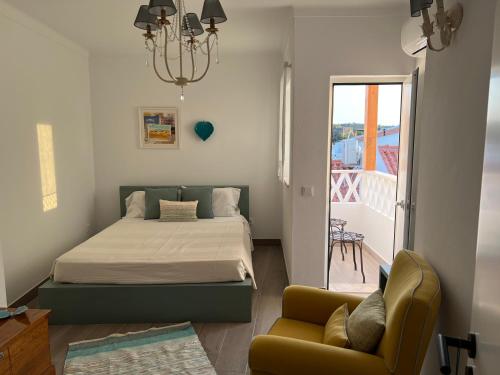 a bedroom with a bed and a chair and a balcony at A Casa Branca in Mértola