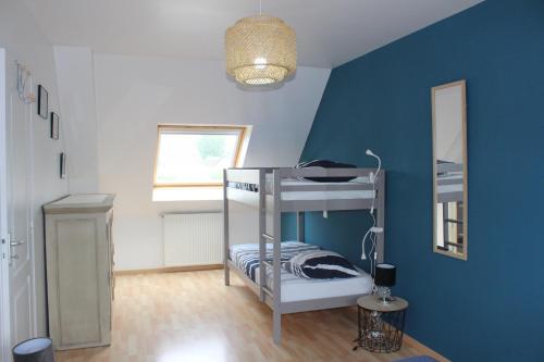 a bedroom with a bunk bed with a blue wall at Les GOELETTES in Bricqueville-sur-Mer