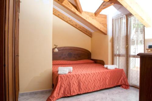 una camera da letto con un letto con lenzuola rosse e una finestra di The Sweet Garret ad Agerola