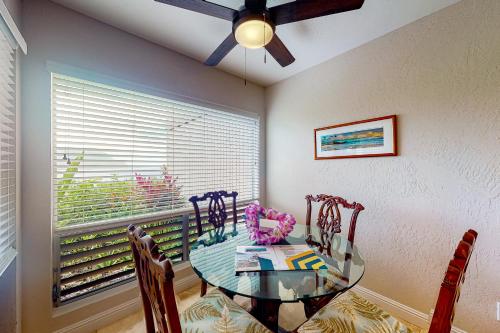 a dining room with a glass table and chairs and a window at Pali Ke Kua 116 in Princeville