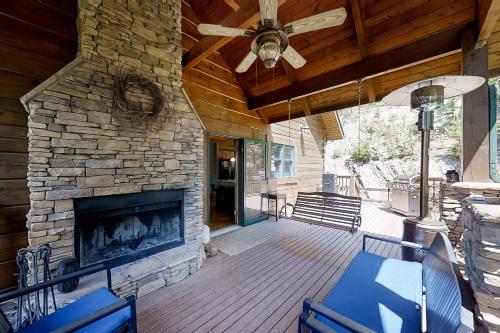 een veranda met een stenen open haard en een plafondventilator bij Crocketts Cabin in New Tazewell
