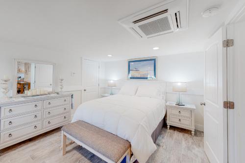 a white bedroom with a bed and a sink at Seas the Day in Kitty Hawk