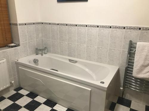 a white tub in a bathroom with a tiled floor at Lissyclearig Lodge in Kenmare