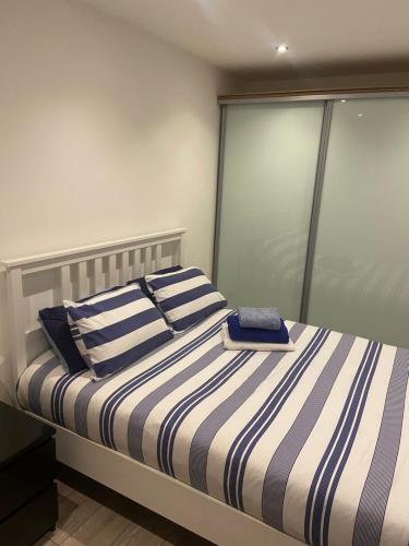 a bedroom with a bed with blue and white stripes at Spacious one bedroom ground floor apartment in Harrogate