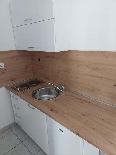 a small kitchen with a sink and white cabinets at Apartments Kovačić in Malinska