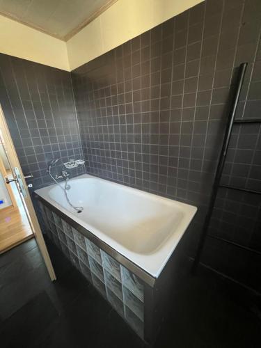 a bath tub in a bathroom with gray tiles at Golden Circle House Ölfusá in Selfoss