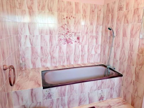 La salle de bains est pourvue d'une baignoire et de carrelage rose. dans l'établissement Holiday Home in Plouguerneau near Beach, à Guissény