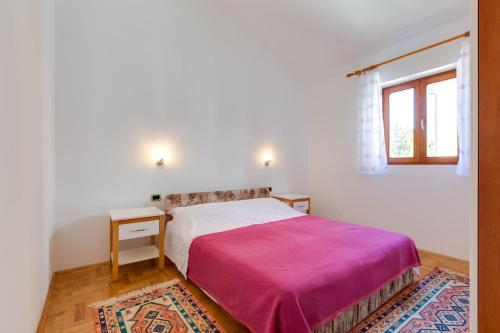 a white bedroom with a bed and a window at Apartments Nives, Artatore in Mali Lošinj