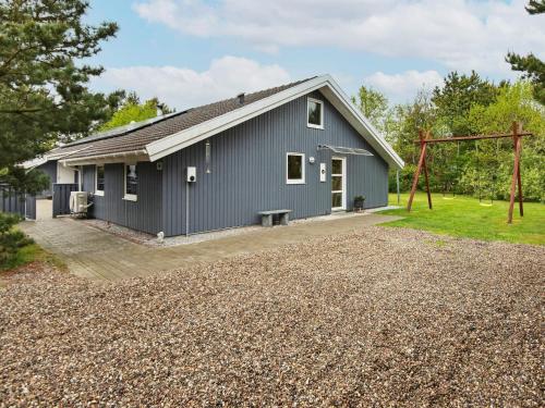 a gray house with a gravel driveway at Luxury Retreat with Pool - By Traum Ferienwohnungen in Nørre Nebel