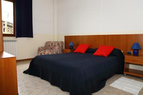 a bedroom with a bed with red pillows and a chair at Holiday home Fattoria Laghetto in Merate