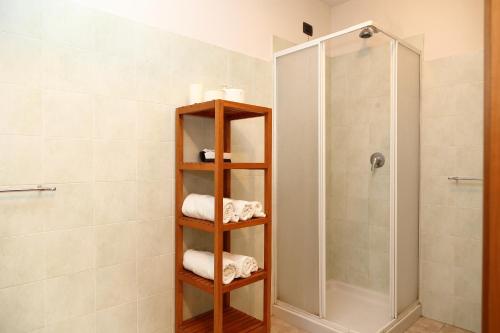 a bathroom with a shower and a wooden shelf with towels at Holiday home Fattoria Laghetto in Merate