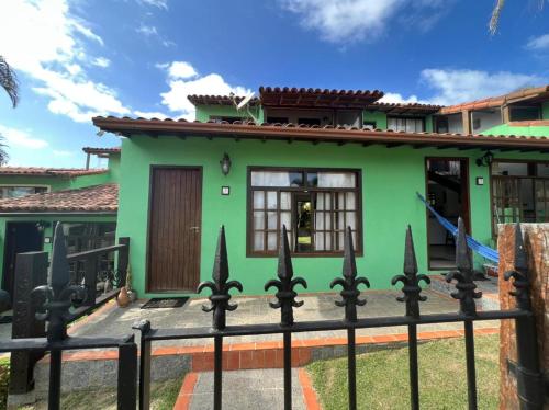 una casa verde con una valla negra en Buzios Casa 2, en Búzios