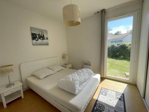 ein Schlafzimmer mit einem Bett und einem großen Fenster in der Unterkunft Maisonnette 4 pers avec terrasse privée et accès piscine, proche océan - Saint-Brevin-les-Pins - FR-1-364-102 in Saint-Brevin-les-Pins