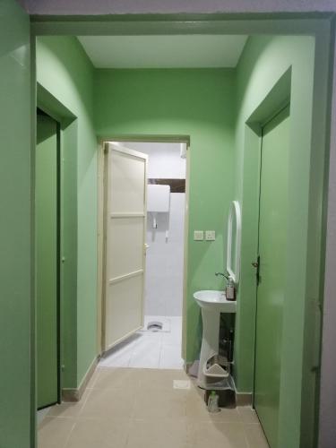 baño con paredes verdes, aseo y lavamanos en استراحة سكنية للإيجار اليومي والشهري, en Az Zulfi
