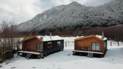 two cabins in the snow in front of a mountain at Snowko in Malalcahuello