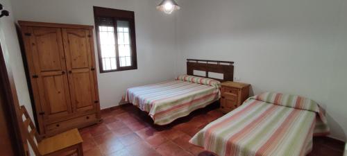 1 dormitorio con 2 camas, armario y ventana en La teja de Olvera, en Olvera